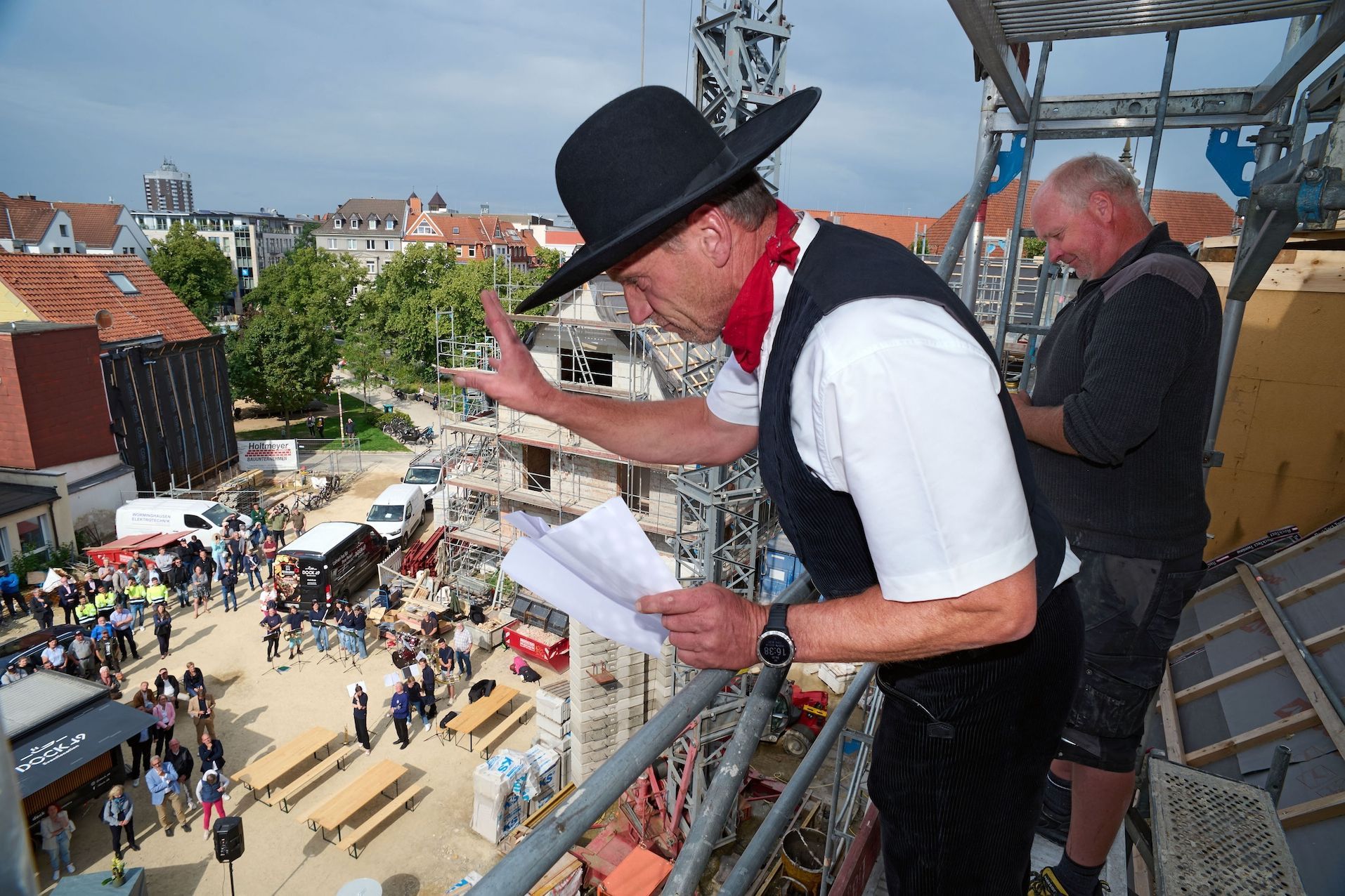 Beim Richtfest: Ein Zimmermann winkt vom Gerüst nach unten.